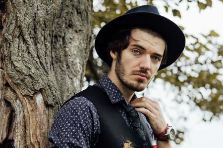 handsome stylish man posing on a green field with cool clothes