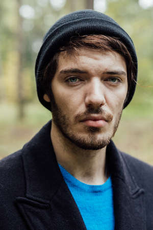 young man with black hat walkink in forest