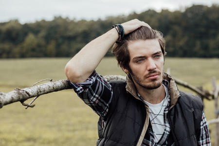 young sexy country boy next to a wooden fence, standing outside in natureの写真素材