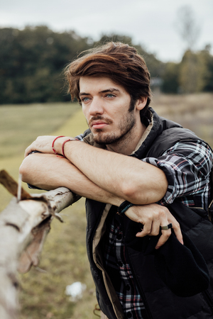 young sexy country boy next to a wooden fence, standing outside in natureの写真素材
