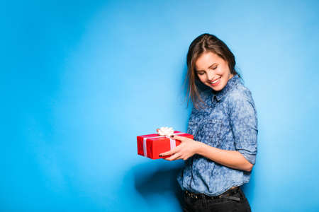 young pretty woman with blue shirt having a red gift in hands