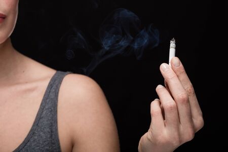 close up of a hand with cigarette, smoking concept on black background
