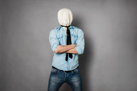 concept with a young man with face covered by a textile material acting normal but having no face, on greyの写真素材