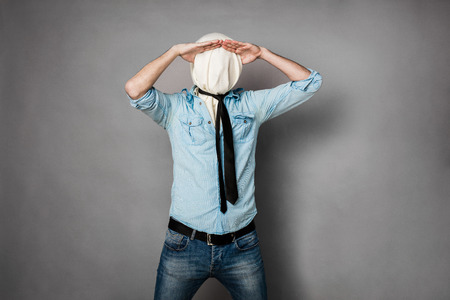 concept with a young man with face covered by a textile material acting normal but having no face,...