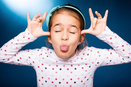 little girl with green headband with bow, pull facesの写真素材
