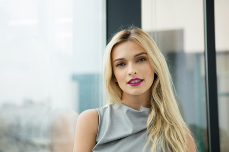 close portrait of a beautiful blonde woman near a large windowの写真素材