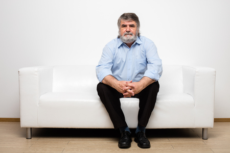 single old men sitting on white couchの写真素材