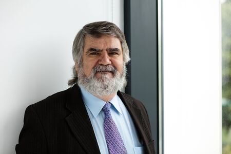 elegant old men with beard standing next to a windowの写真素材