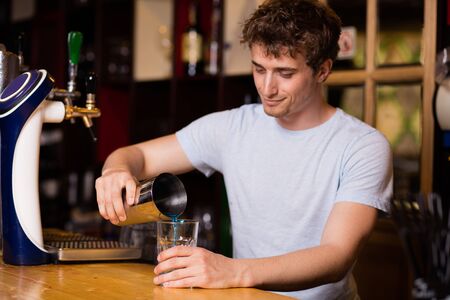 young bartender preparing blue coktail in a pubの写真素材