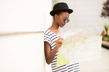 young black student traveling and checking the map outside the streetの写真素材