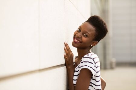 smiling young black woman in striped shirt standing outsideの写真素材