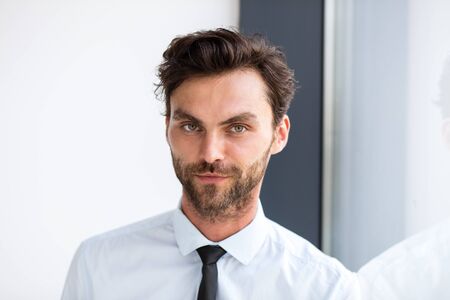 businessman in suit standind next to an office building windowの写真素材