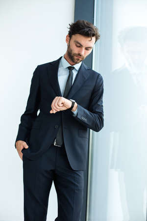 businessman in suit standind next to an office building windowの写真素材