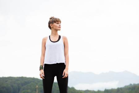 young athletic woman stretching and preparing to do sport somewhere in nature on top of the...