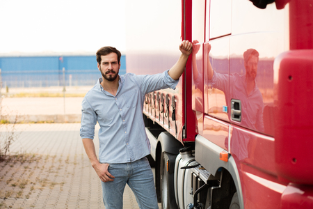 handsome masculine driver stranding next to his red truck outsideの写真素材