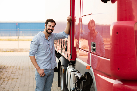 smiling handsome masculine driver stranding next to his red truck outsideの写真素材