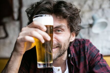 close up of a guy behind his glass of beer, smilingの写真素材