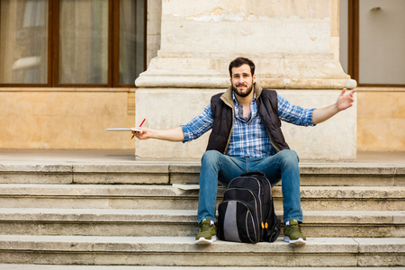young student sitting outside on university stairs hinking about his examsの写真素材