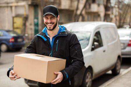 Delivery man with cap and cardboard in handsの写真素材