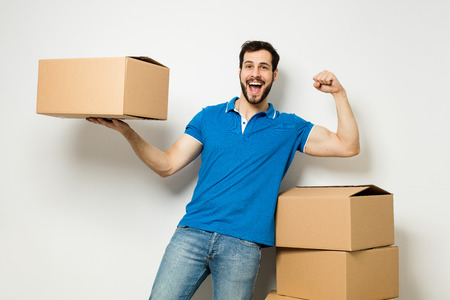 strong man showing his muscles next to a stack of cardboard boxesの写真素材
