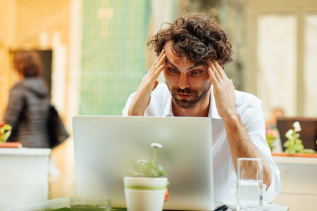 handsome elegant man working outside at a cafe table, focused on his laptopの写真素材