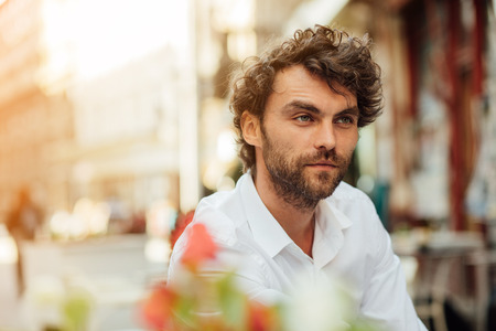 handsome masculine man sitting at terrace alone, elegant dressed, outdoorの写真素材