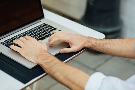 close up of hands typing at laptop outdoor on elegant terrace tableの写真素材