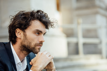 handsome man sitting outside concerned on the stairs waiting for someone or somethingの写真素材