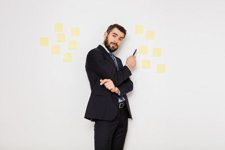 elegant man in suit presenting some postit on the wallの写真素材