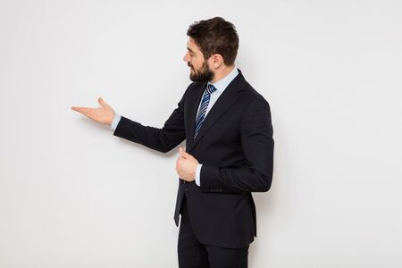elegant confident man in suit with tie standing against a white wallの写真素材
