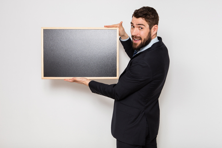 elegant businessman standing and showing a empty blackboard on white backgroundの写真素材