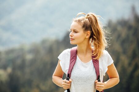 portrait of a young and beautiful woman with her backpack in the mountains