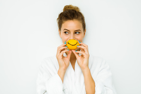 young beautiful woman standing on a white wall in bath towel playing with her favorite fruit, the lemonの写真素材