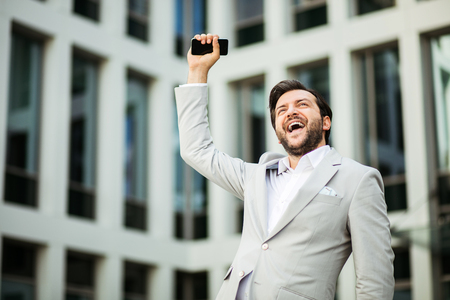 succesfull businessman very excited in front of an office buildingの写真素材