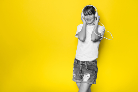 young and beautiful woman listening music with white headphones on isolated on yellow backgroundの写真素材