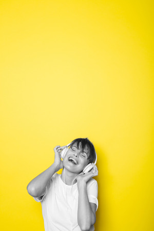 young and beautiful woman listening music with white headphones on isolated on yellow backgroundの写真素材
