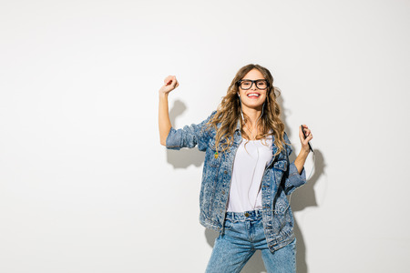 listen to the music and dance. concept with a young expressive beautiful woman in retro jeans outfit...