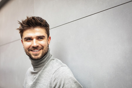 smiling attractive man on gray modern wallの写真素材