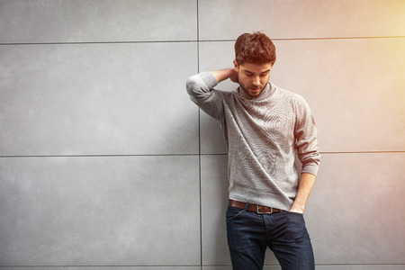 sexy man having one hand behind his neck on gray backgroundの写真素材