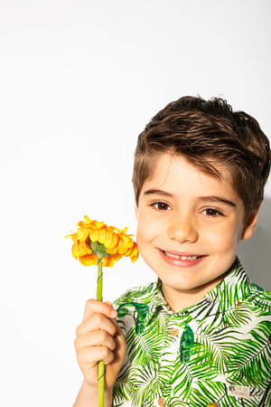 spring is here, happy kid posing with a flower on white backgroundの写真素材