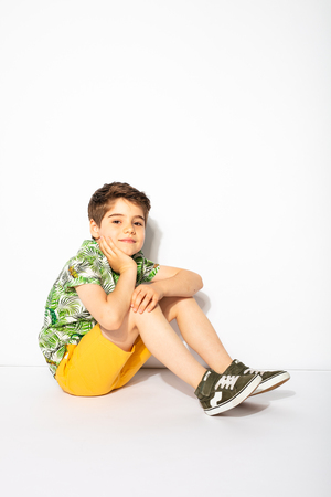 little energetic kid sitting on the floor and looking to camera with smileの写真素材