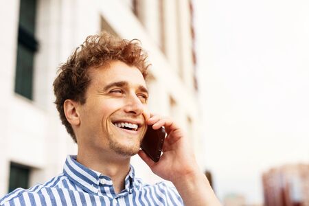 clouse up portrait of a handsome man having a nice conversation at cellphone outside, smiling and enjoying talkingの写真素材