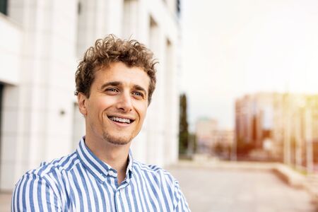 portrait of a young and happy man with blonde and curly hair smiling and inspiring successの写真素材