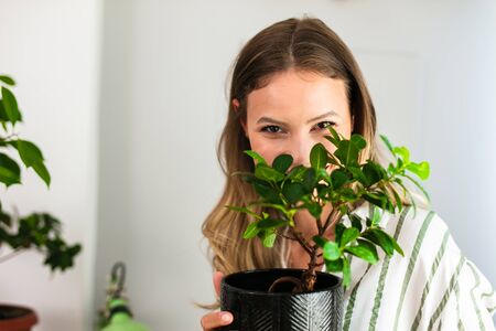 take care and love your house plants, young woman holding a bonsai in her arms with joy and love, home healthy activityの写真素材