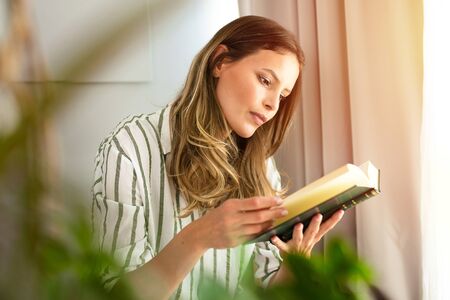 find your chilling place inside your house and read a book, young woman reading a book next to a...