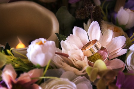Wedding rings lie on the Bridal bouquet of roses and peonies.