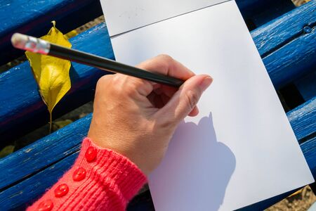 A blank notepad for planning, summing up. Hand holds pencil. She will draw or keep a notepad.の写真素材