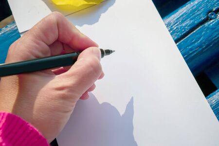 A blank notepad for planning, summing up. Hand holds pencil. She will draw or keep a notepad.の写真素材