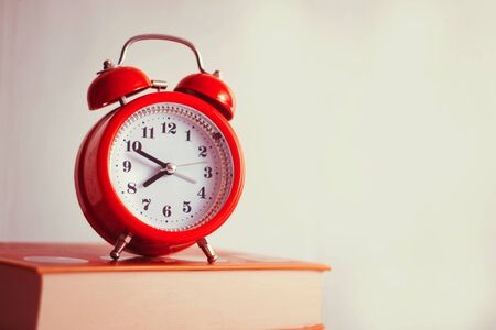 Alarm clock and old books on the shelf in the morning, concept of education and reading
