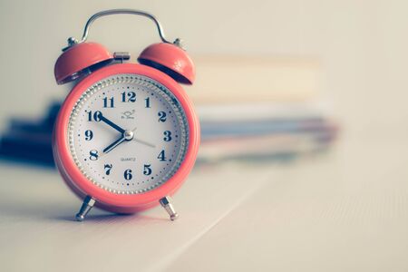 Alarm clock and old books on the shelf in the morning, concept of education and readingの写真素材